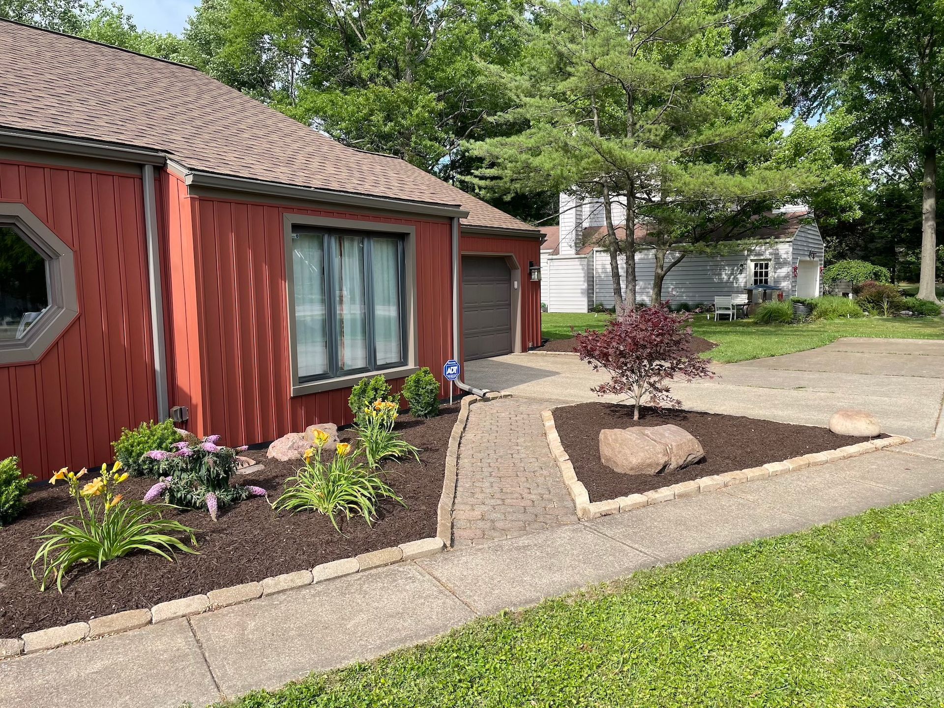 A red house with a garage and a walkway leading to it.