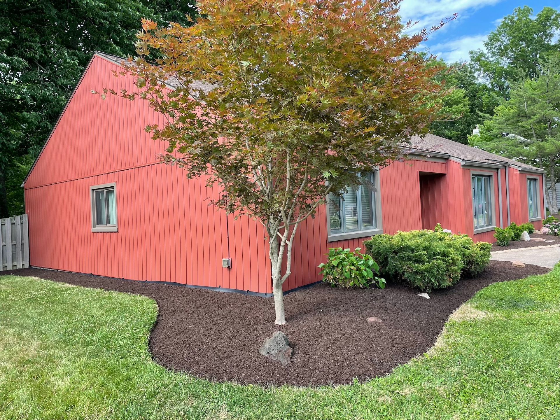 A red house with a tree in front of it.