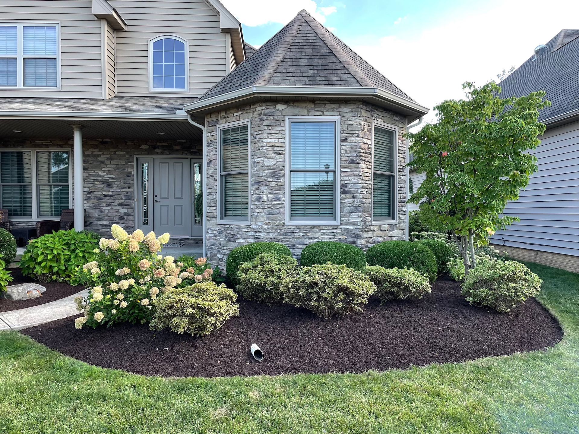 The front of a house with a circular garden in front of it.