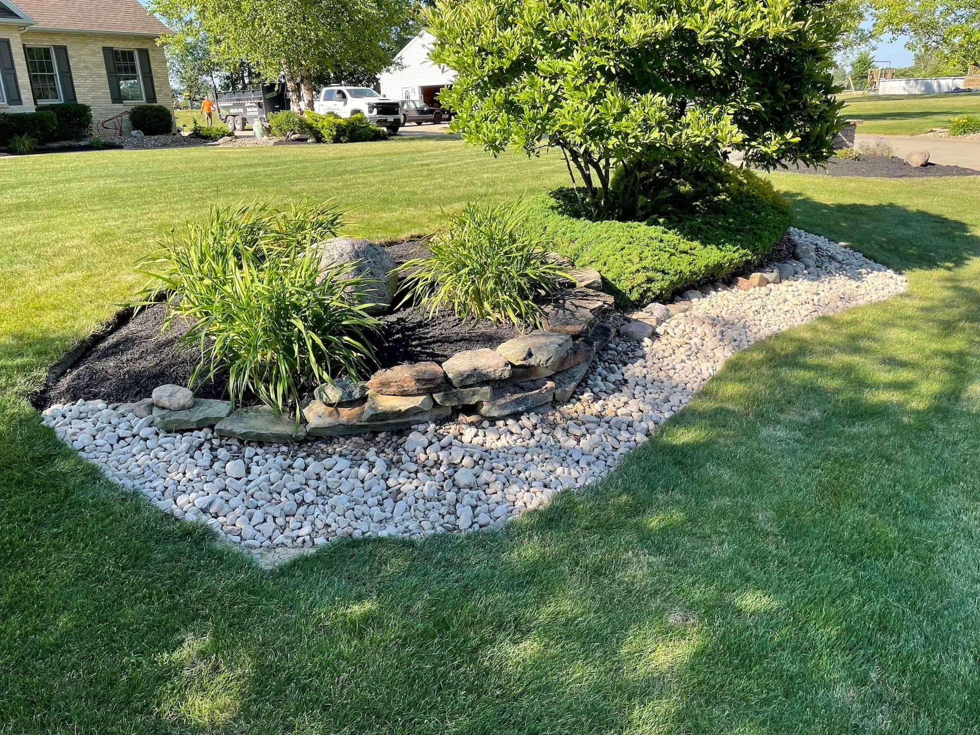 A garden with rocks and plants in front of a house.