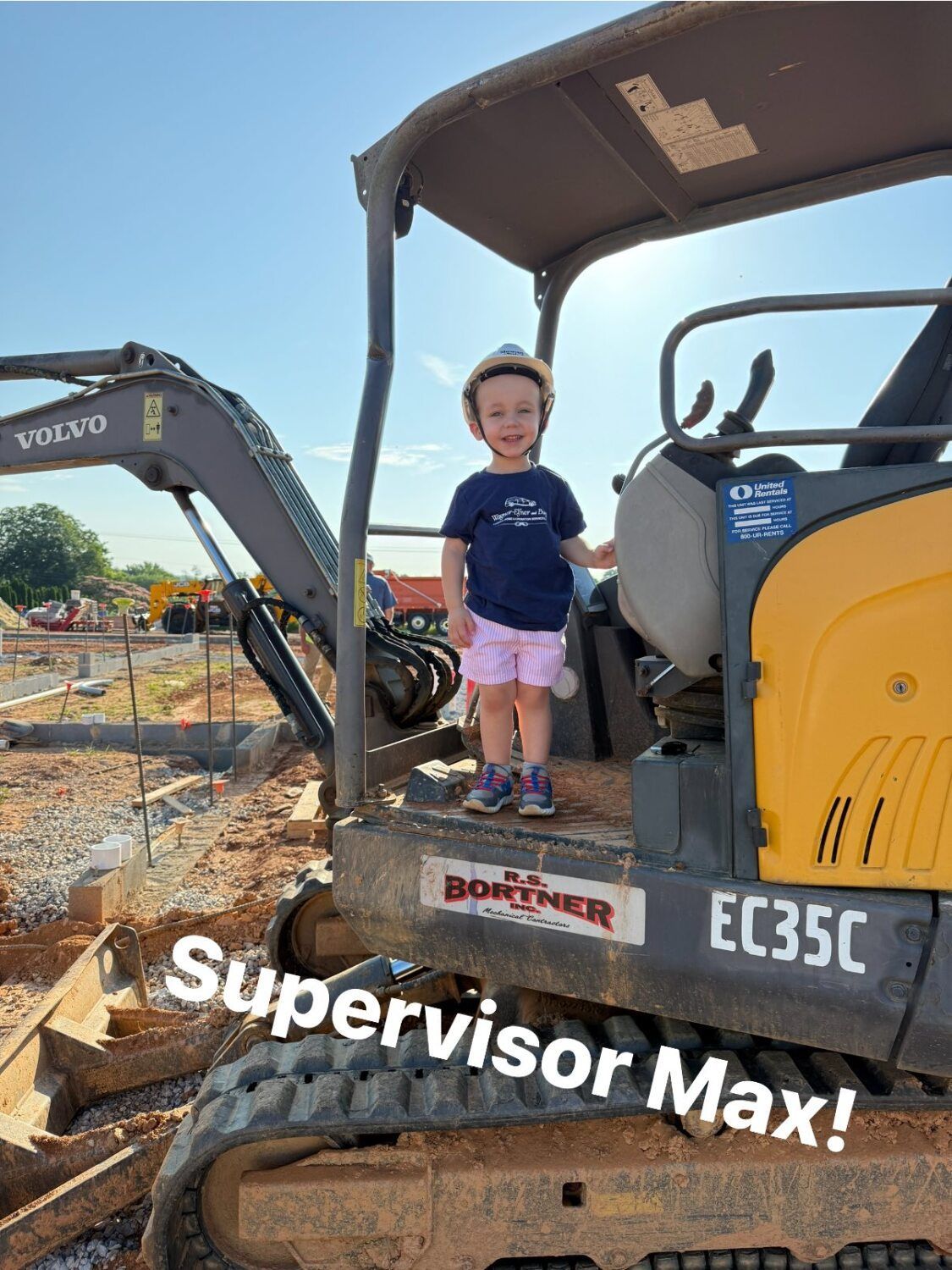 Young child in a hard hat stands on an excavator, text reads