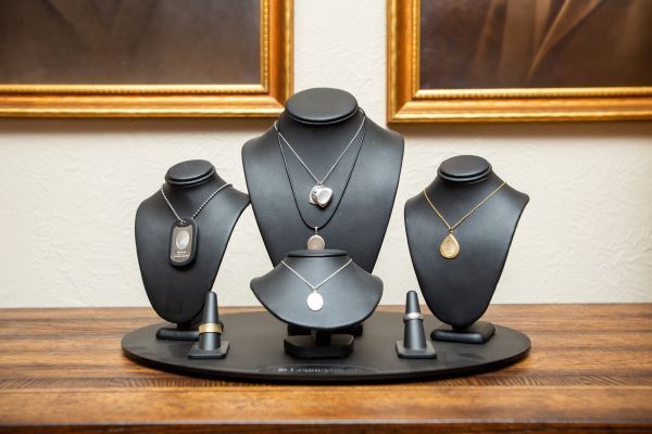 Memorial fingerprint necklaces and rings arranged on black busts for personalized remembrance