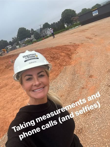 Woman in a hard hat smiles, taking selfie at a construction site. Text says, “Taking measurements and phone calls (and selfies)”.