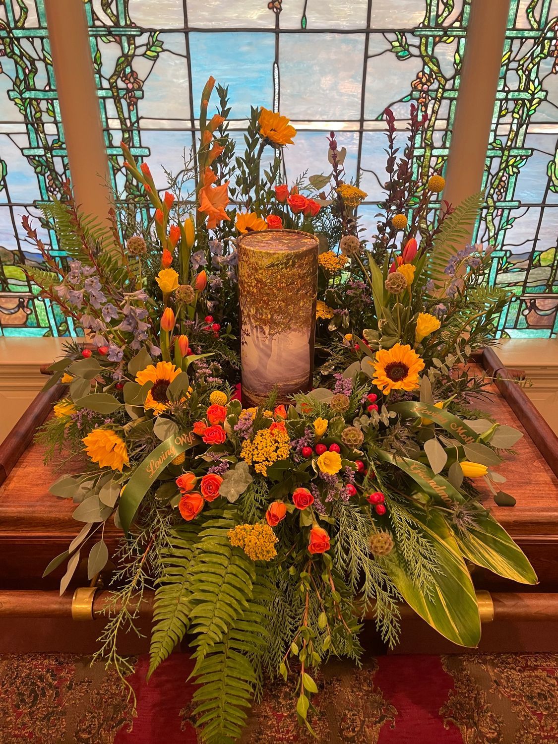 Wooden casket topped with floral arrangements displayed inside a church during funeral services