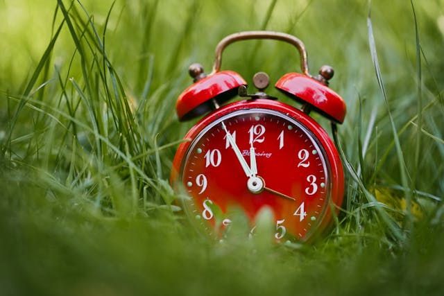 Vintage red clock in grass honoring cherished time at Funeral Homes York, PA