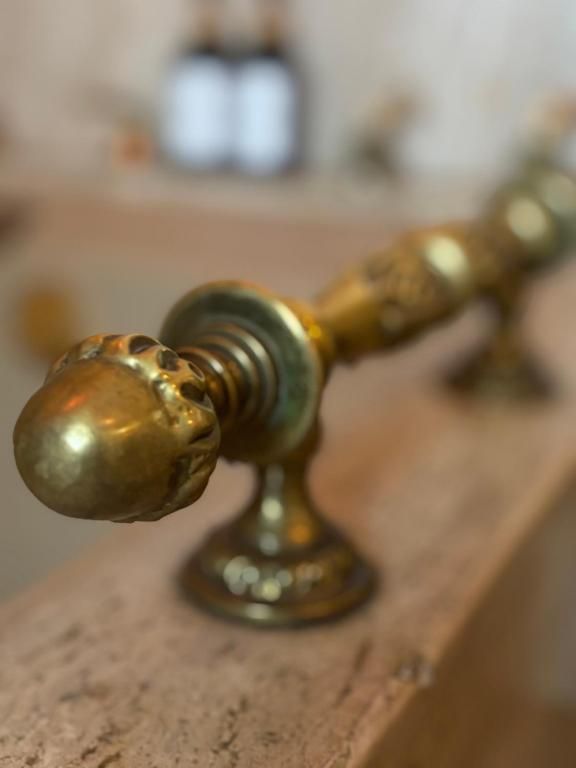 Manija de puerta de latón dorado con extremo en forma de bellota, montada sobre una superficie de madera texturizada.