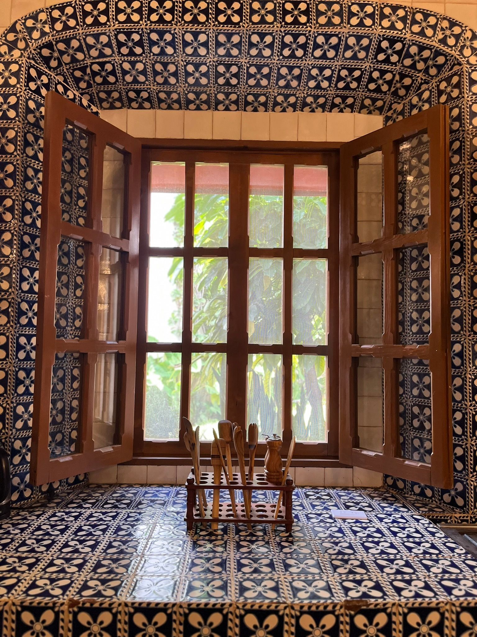 Ventana de madera con contraventanas abiertas revestidas de azulejos azules y blancos.