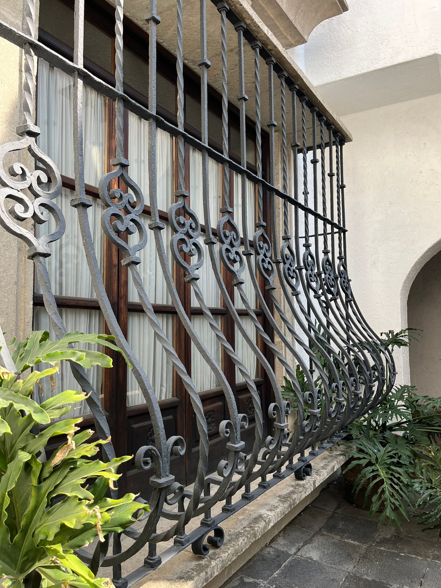Barras de ventana de hierro adornadas con volutas decorativas.