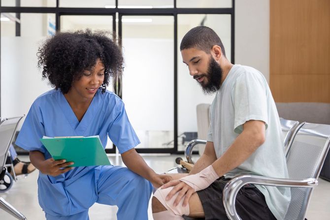Healthcare worker showing a tablet to a seated patient in a bright clinic room