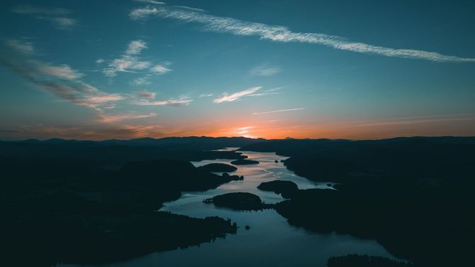 Sunset over a river winding through dark hills under a blue-orange sky