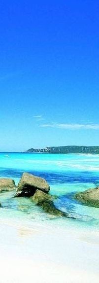 A painting of a beach with rocks in the water and a blue sky.
