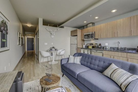 Open-concept living area with a blue sofa, dining table, and full kitchen.