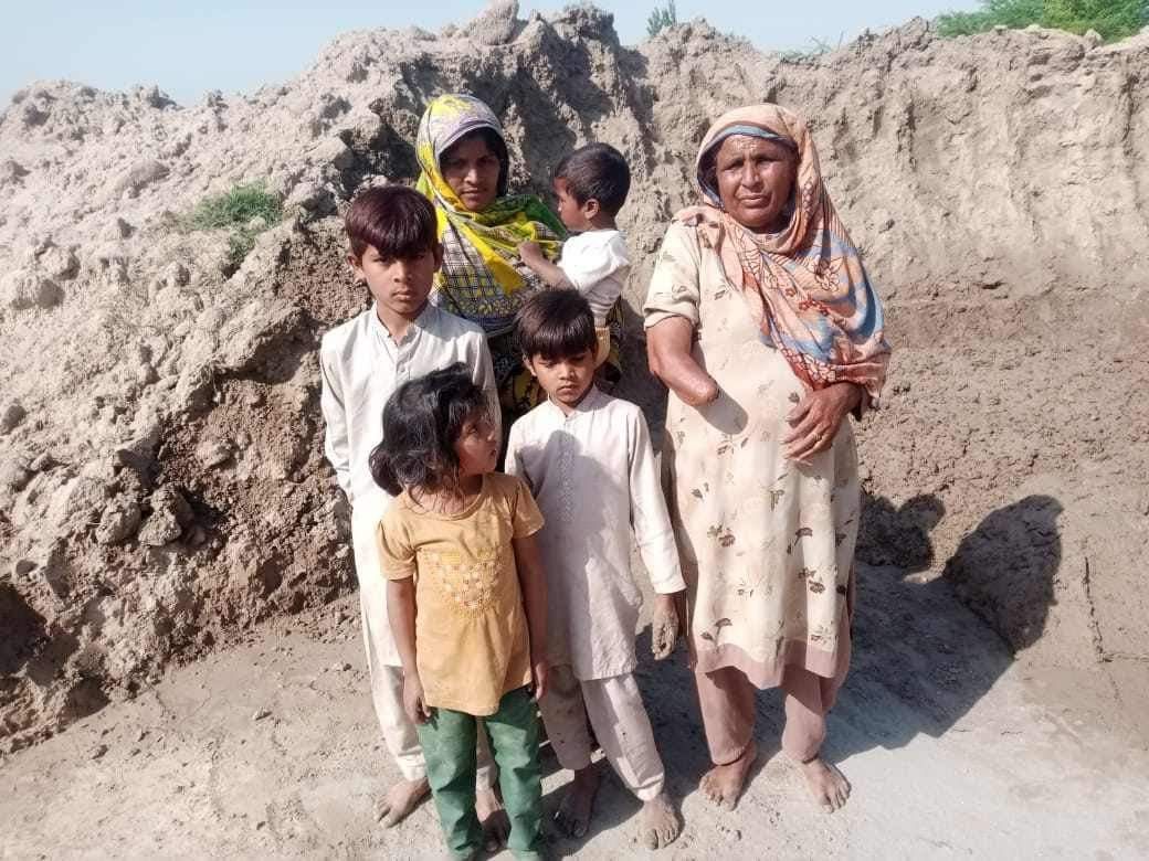 Family standing together outdoors near a sandy hill.