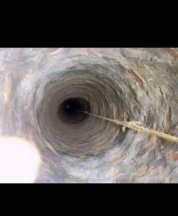 Looking down a deep, circular well. A rope descends into darkness.