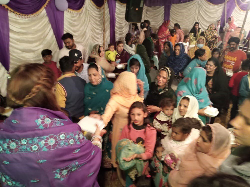 People gathered inside a decorated venue, possibly for an event. Several women and children are visible.