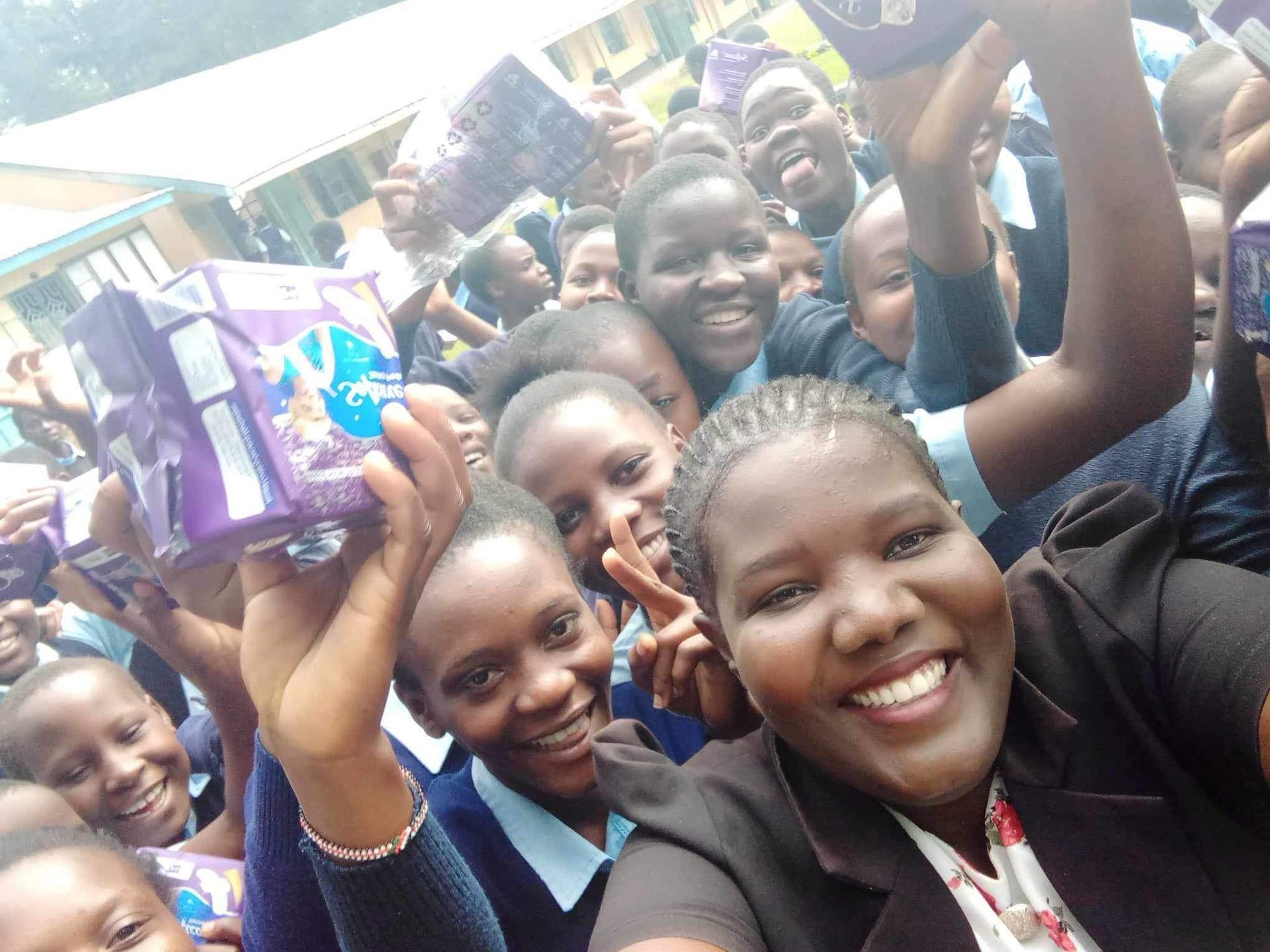 Group of smiling students holding packages, outdoor setting.