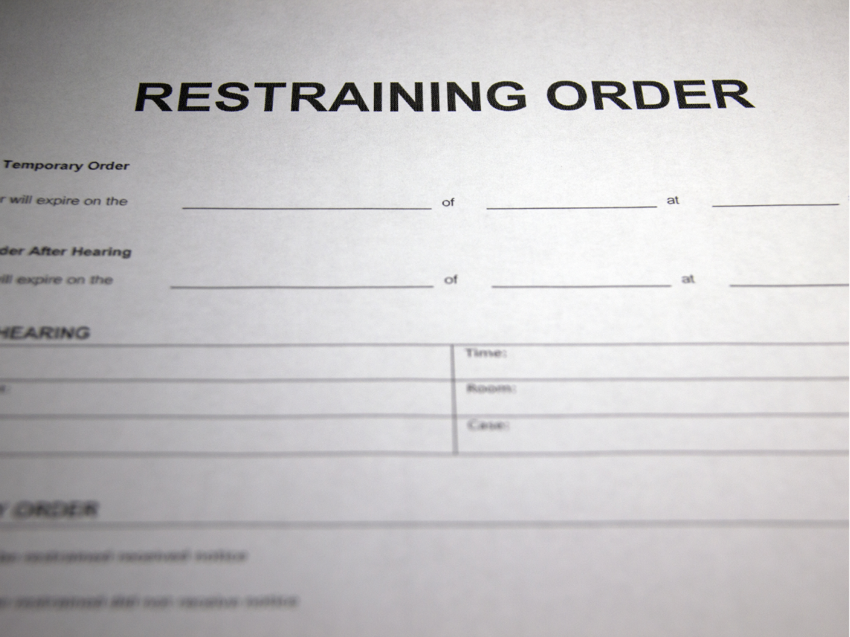 Blurry close-up of a restraining order form with bold title and blank fields.