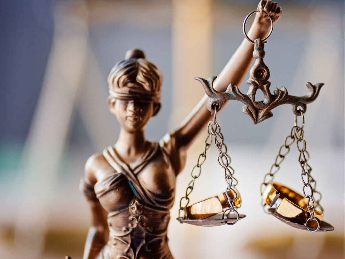 Justice scale held by a bronze Lady Justice figurine, with blurred background