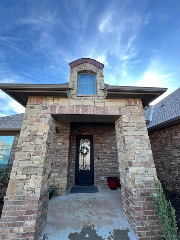 Stone house entryway with arched porch and blue sky above
