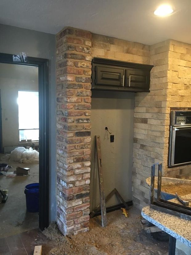 Kitchen nook with exposed brick walls, dark cabinets, and a granite countertop under construction