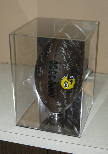 Signed black football in a clear display case on a shelf