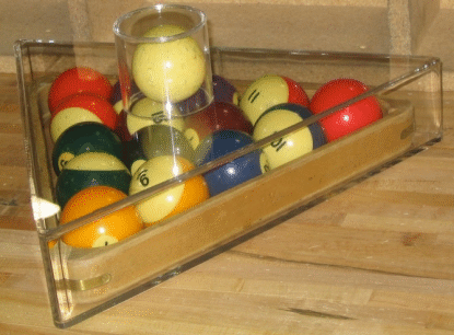 Pool balls in a clear triangular rack on a wooden table, with a central cue ball-like white ball.