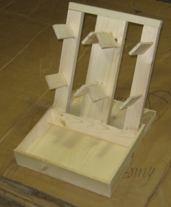 Wooden tabletop display stand with angled slats and small shelves on a cardboard surface
