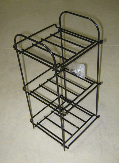 Black metal wire countertop rack with three shelves and a curved handle.