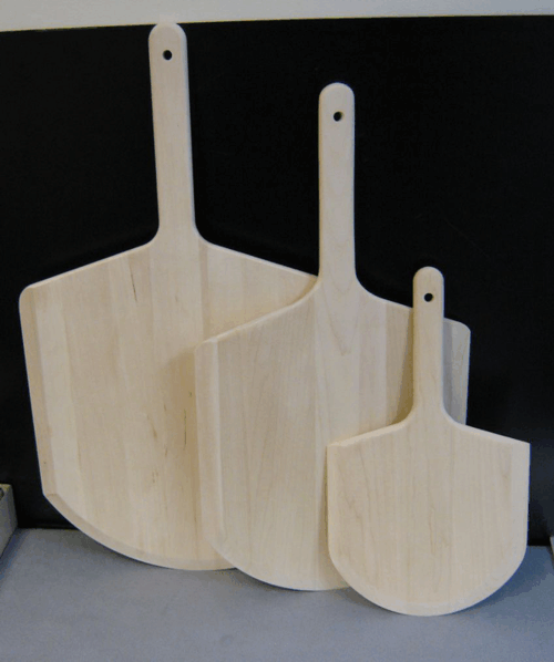Three light wood cutting boards of different sizes leaning together against a dark background