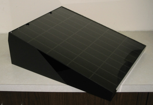 Black rectangular slanted device with a gridded top on a tabletop