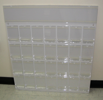 Clear acrylic pocket organizer with multiple small compartments against a wall