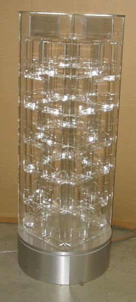 Clear cylindrical glass lamp with a silver base, lit from inside by many small bulbs.