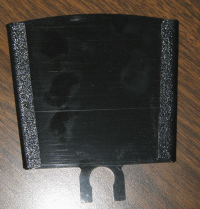 Black rectangular plastic part with silver textured edges and a U-shaped cutout at the bottom.