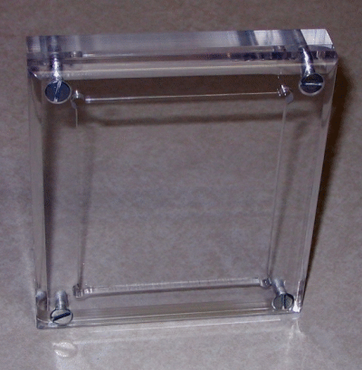 Clear acrylic wall-mounted display or frame with metal corner mounts on a beige background