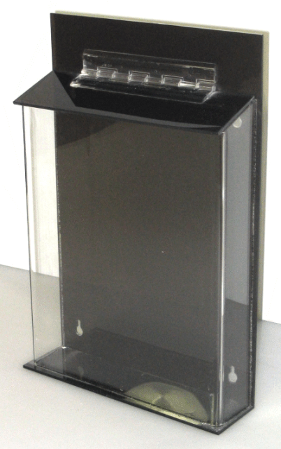 Black wall-mounted dispenser with clear front panel and small slanted top shelf
