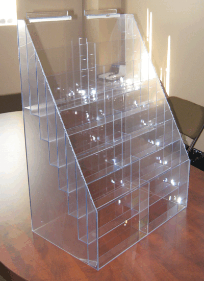 Clear acrylic countertop display rack with multiple stepped shelves on a wooden table