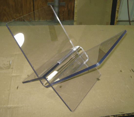 Clear acrylic stand with blue-edged panels on a beige surface, viewed from above.