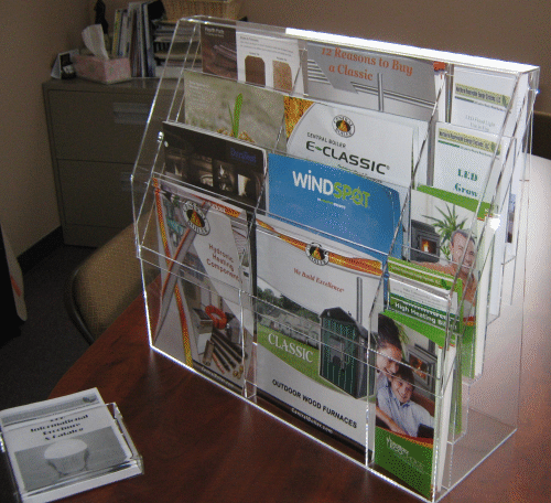 Clear acrylic brochure display on a desk holding assorted flyers and pamphlets.
