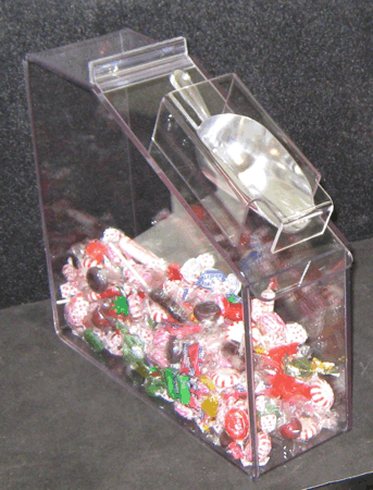 Clear acrylic candy dispenser filled with colorful wrapped candies on a dark background