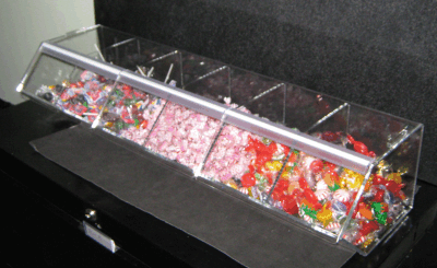 Clear acrylic candy display case filled with colorful assorted sweets on a black counter