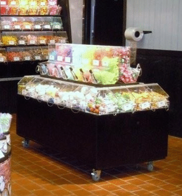 Candy display on a black cart, with colorful wrapped treats in a shop aisle.