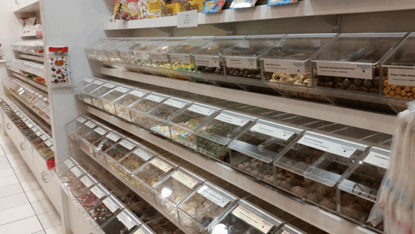 Bakery display case with rows of assorted pastries in clear bins and trays