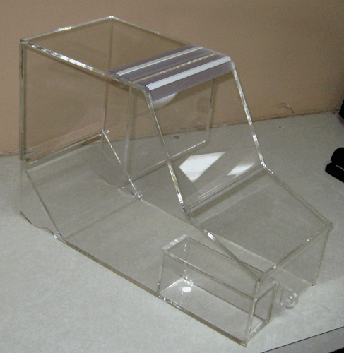 Clear plastic multi-tier display stand with angled shelves on a tabletop.