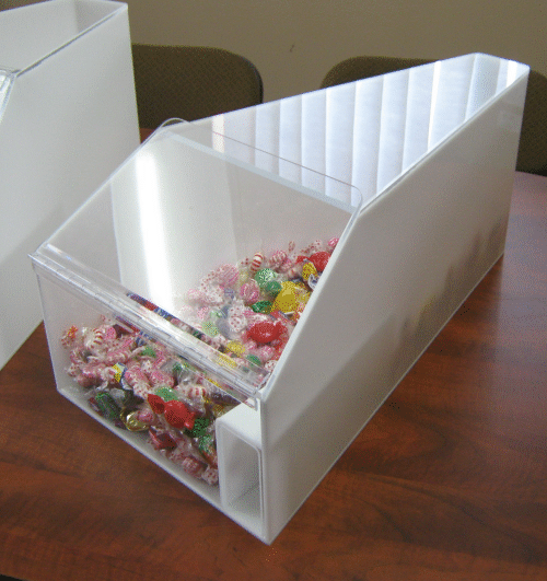 Clear acrylic candy display box filled with colorful wrapped candies on a wooden table
