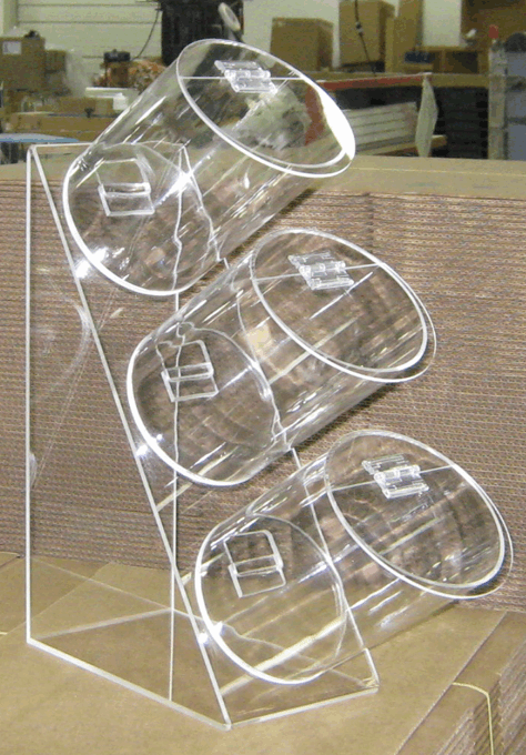Transparent tilted rack holding three clear plastic cups in a store or workshop setting