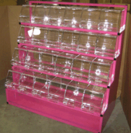 Pink multi-tier acrylic display rack with clear compartments, shown indoors on a concrete floor