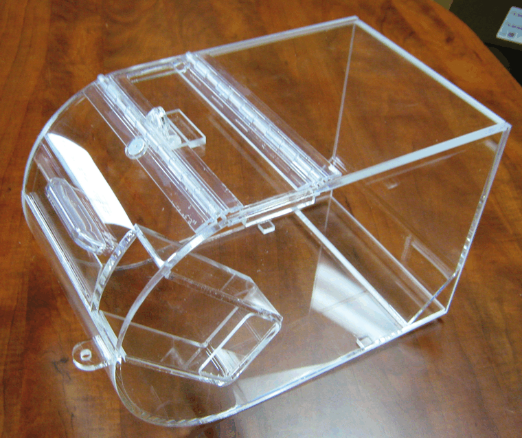 Clear acrylic pet transport carrier on a wooden floor, with curved front opening and top latch.