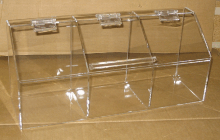 Clear acrylic three-compartment tabletop storage box with hinged lids on a cardboard surface