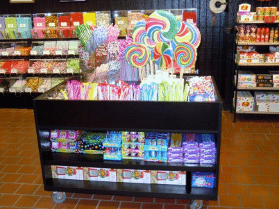 Colorful candy display in a store, with lollipops and assorted sweets on shelves.