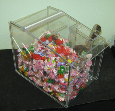 Clear plastic box filled with colorful wrapped candies on a black table